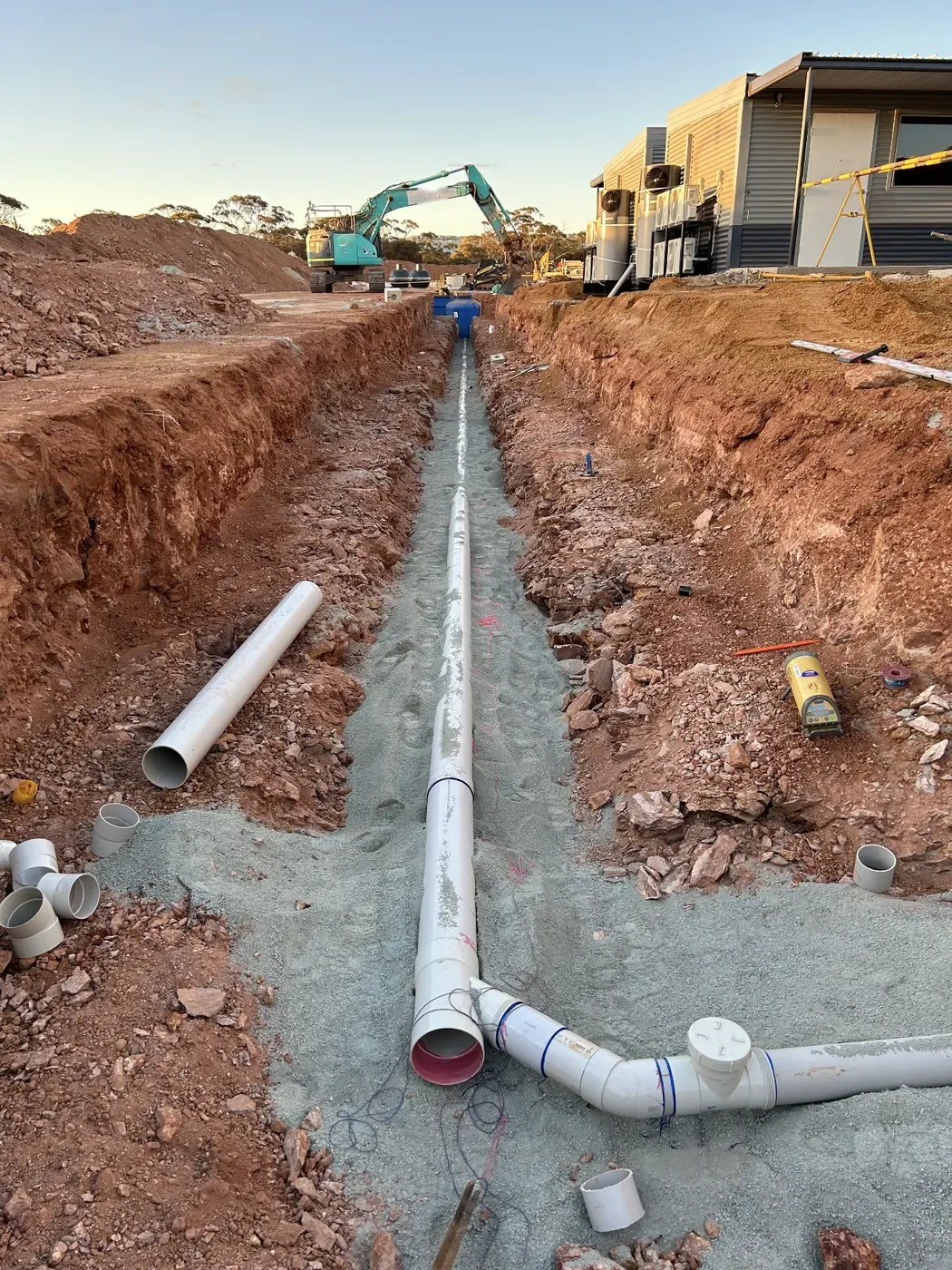 An excavator working at the end of a pipe trench